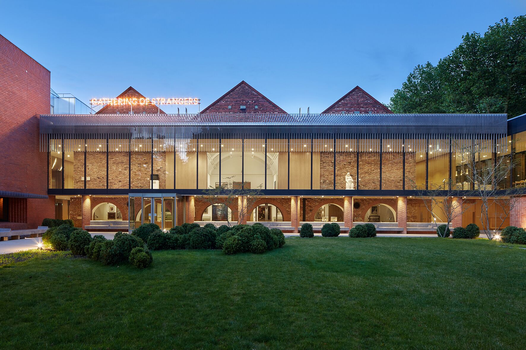 museum with contemporary glass extension and gardens, seen at dusk.