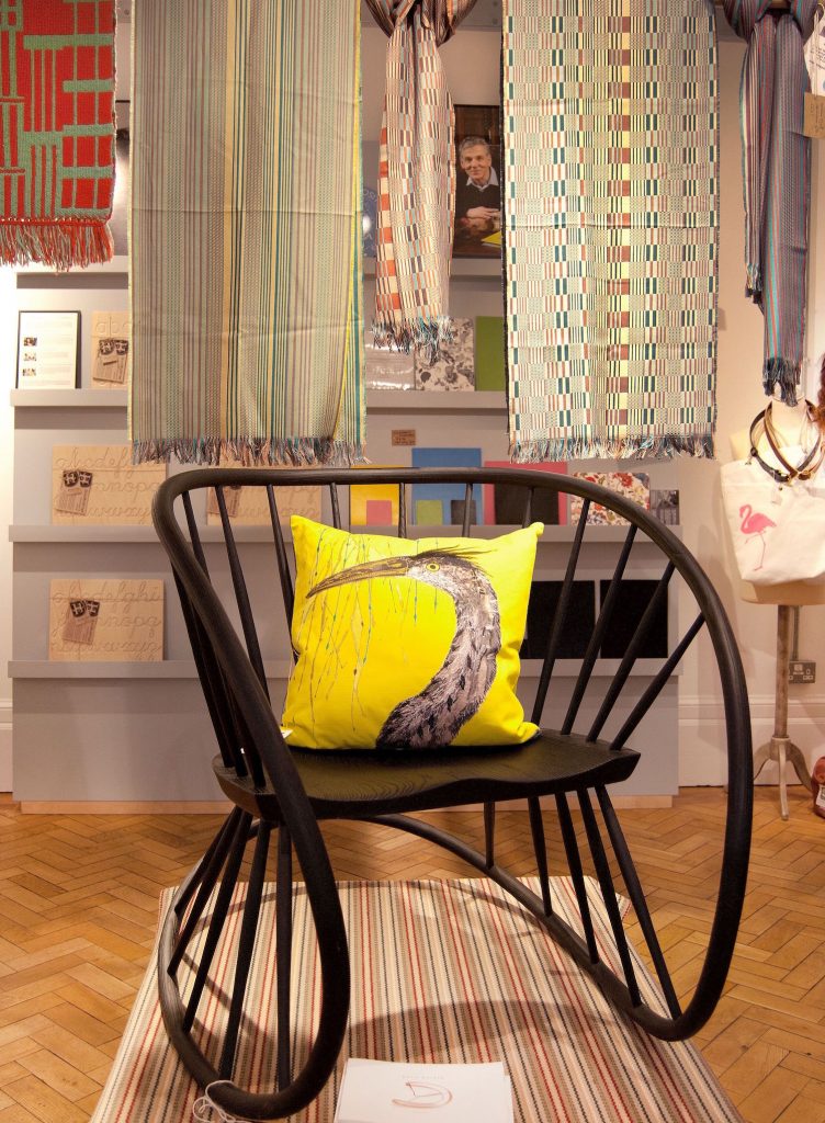 black rocking chair with a yellow cushion with woven fabric hanging above