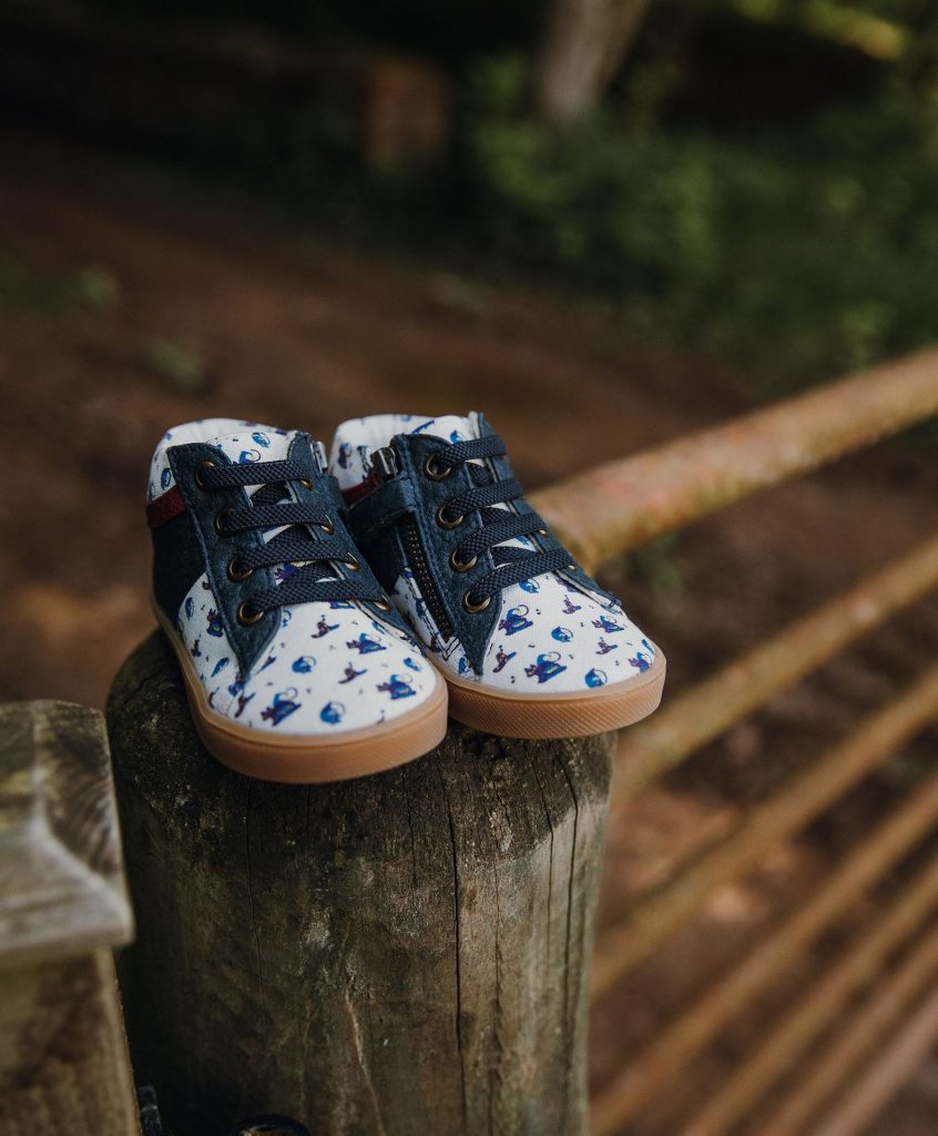 blue children's shoes on a gate post, at the entrance to a woodland