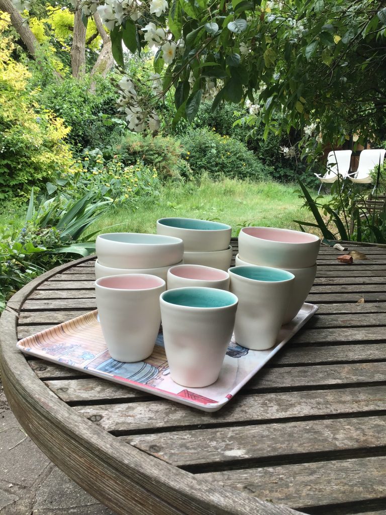Linda Bloomfield cups on a tray, set on a wooden table, in a garden