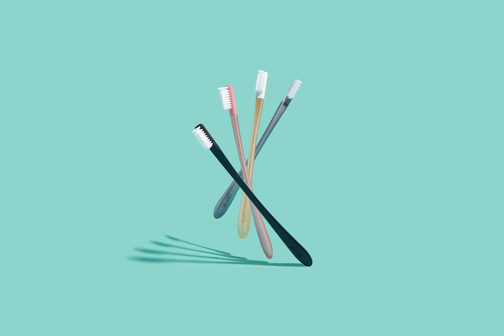 three tooth brushes on a green background