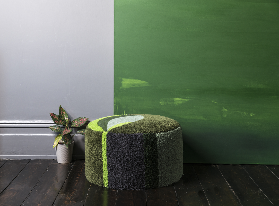 Judi Archer footstool in green and pale grey, against a green abstract painting showing Homes with A Heart