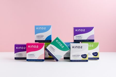 Stacked bars of solid, sustainable shampoo by Kind 2, on a pink background.