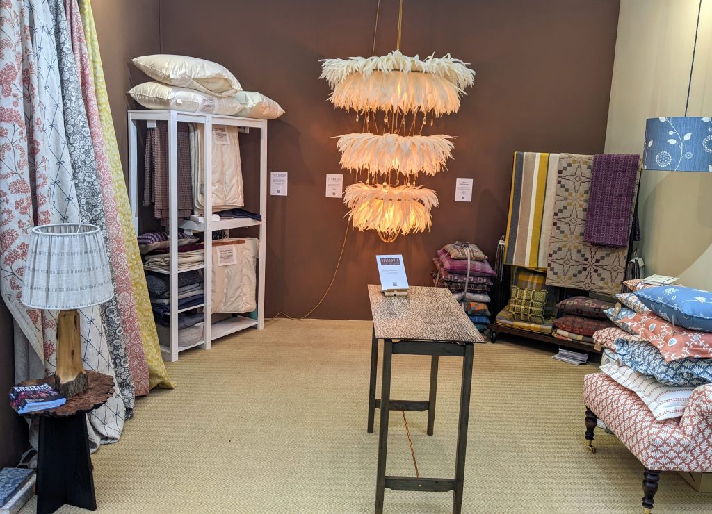 stand design at Decorex with textiles, a light, table and a brown wall
