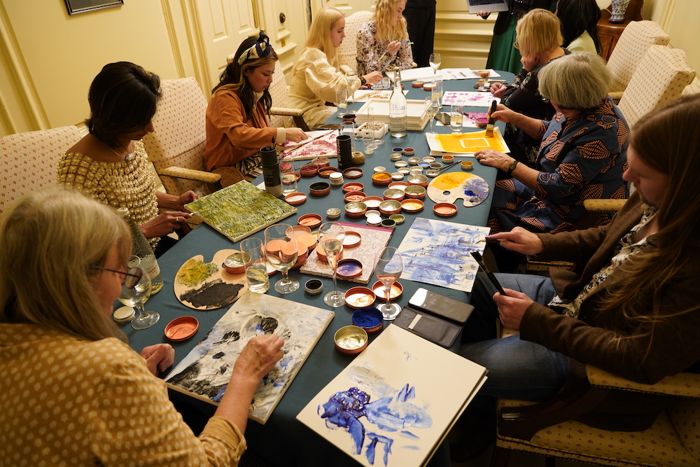 Group of eight people painting around a table, using sustainable artists paints.