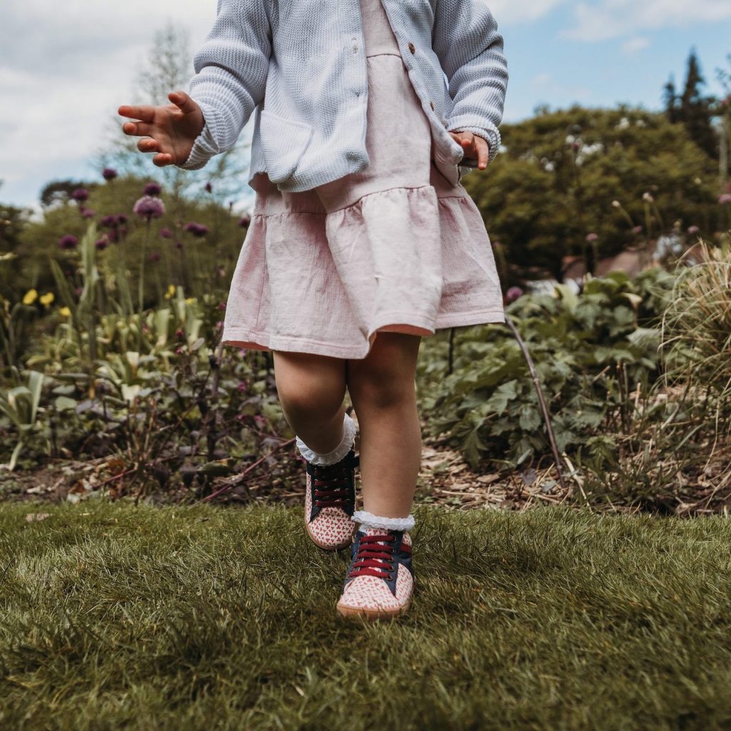 child running an a summer garden in sustainable, vegan shoes, by Pip & Henry