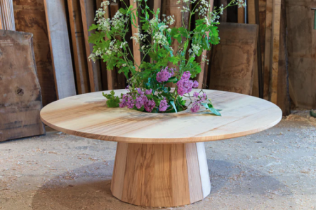 Circular wooden table with flowers in the middle by John Eadon